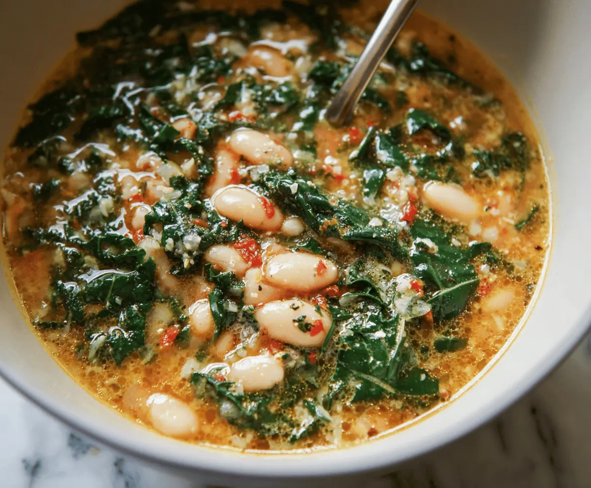 A bowl of hearty White Bean and Kale Soup garnished with fresh herbs, showcasing tender beans, vibrant kale, and a flavorful broth.